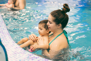 a small child is engaged in swimming with his mother at a swimming school.Mother and child in swimming pool.