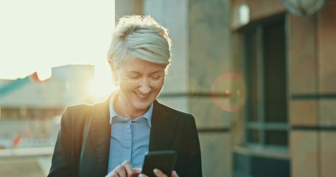 Phone, woman and ceo walking in city, lens flare and sunset to travel outdoor. Mobile, senior and happy business consultant in street typing email online, social media meme and funny laugh for comedy