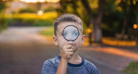 boy looks into a magnifying glass. Selective focus
