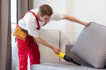 Obraz premium Man dry cleaner's employee hand in protective rubber glove cleaning sofa with professionally extraction method. Early spring regular cleanup. Commercial cleaning company concept.