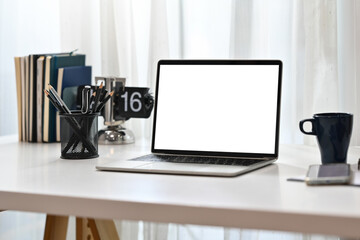 Home office desk with laptop computer, coffee cup and pencil holder