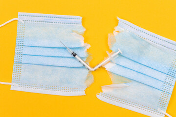 Anti Vaccine Movement and Anti Mask Concept - Broken Medical Syringe and Torn Medical Face Mask...
