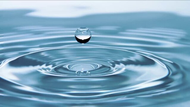 A close-up photo of a drop of water hitting the surface of a clear pool of water. The drop creates a perfect circle, with ripples spreading out in all directions.