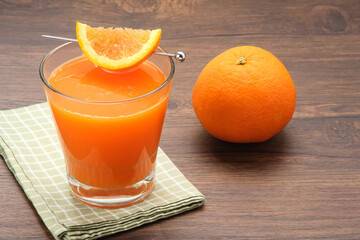 Orange juice in glass, cold pressed juice with fresh fruits on wooden table
