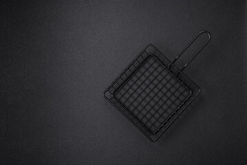 A black mesh or basket for deep-frying and cooking potatoes in boiling oil