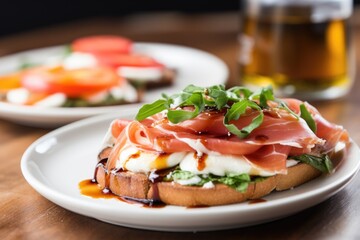 close-up of an open-face prosciutto sandwich and caprese salad