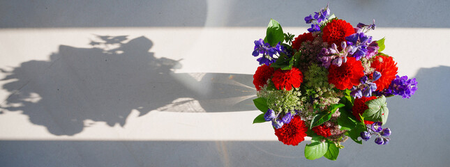 view from above of a bouquet of flowers in a vase casting long shadows 