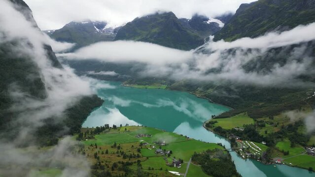 Oldevatnet Glacier Lake and Mountain Valley covered in clouds in Norway, Loen, Vestland - Aerial Circling
