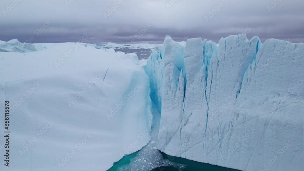 Wall mural aerial view flying between the iceberg peaks and large icebergs floating in ilulissat icefjord, arct