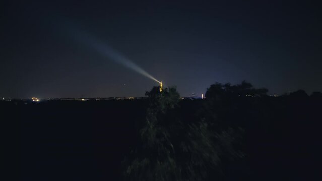 Aerial night shot of Paris city lights and Eiffel tower spinning spotlight 