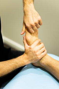 Vertical photo of an unrecognizable physiotherapist or podiatrist examines the foot of a patient suffering from a bunion in a modern clinic. Massages in bunions. Hallux Valgus