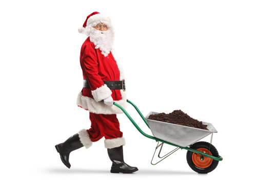 Full length profile shot of a santa claus pushing a wheelbarrow with soil