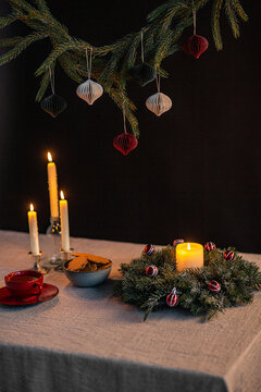 winter holidays and celebration concept - close up of christmas wreath, gingerbread and candles on table over black background