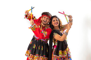 Portrait of happy young couple performing Dandiya Raas over white background
