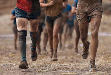 Group of participants in an obstacle course race running. They run very muddy. Concept of hardness and effort