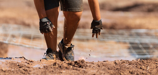Mud race runners. Crawling, passing under a net obstacle during extreme obstacle race