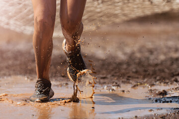 Mud race runners. Crawling, passing under a net obstacle during extreme obstacle race