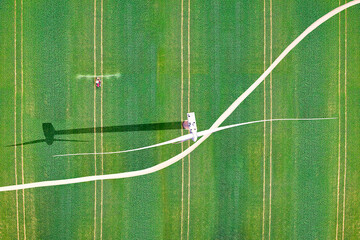 Aerial view of wind turbine and a crops sprayer tractor over a green agricultural field in Spain....