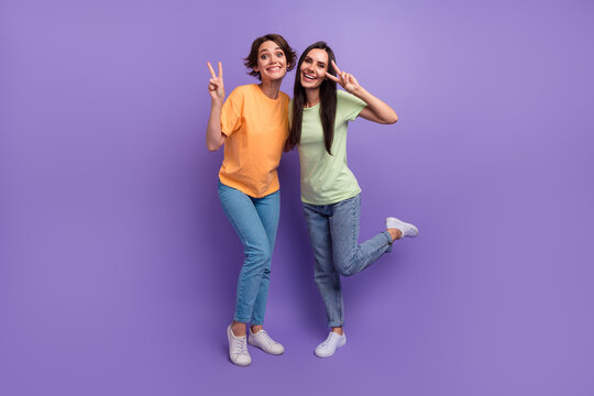 Full body photo of funny girlfriends careless show v sign peace for ukraine symbols stop war make love isolated on violet color background - Powered by Adobe