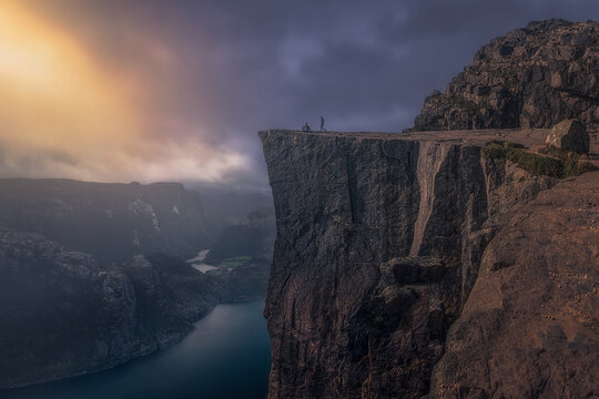 The first rays of sunrise at Preikestolen. A couple of tourists on Preikestolen (Pulpit Rock) enjoy the first rays of sunrise. Preikestolen, Pulpit Rock, Rogaland, Norway