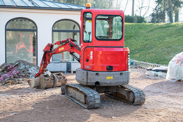 Small red excavator. Construction excavator in a construction site.