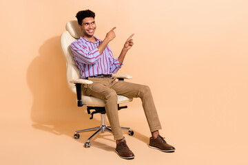 Full length photo of intelligent guy dressed shirt sit on armchair look directing at offer empty space isolated on beige color background