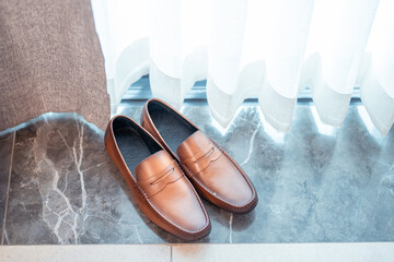 brown leather male shoes on a marble floor along the window.