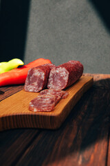Sausage on a wooden tray with green and red paper. Set of smoked sausage on dark wooden background. Front view