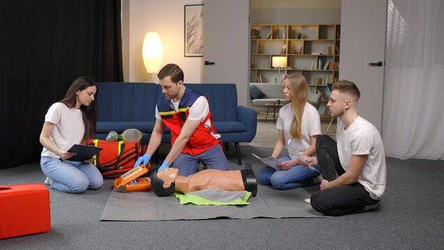 First aid measures for victims. Basic emergency training in group, man showing artificial lung ventilation on mannequin, indirect heart massage