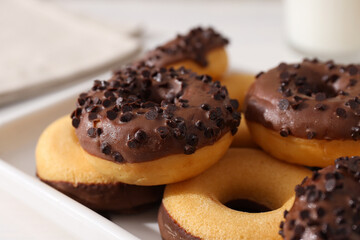 Chocolate donuts on plate on light background, close up