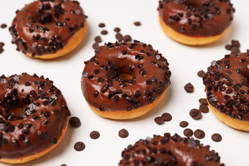 Chocolate donuts and chocolate chips on white background, close up