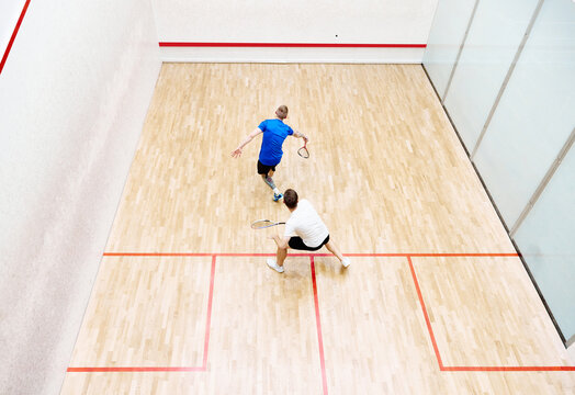 Top view of two young men, friends, sportsmen playing squash on squash court. Competition. Concept of sport, hobby, healthy and active lifestyle, game, gym, ad