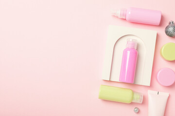 Cosmetic bottles and white decoration on pink background, space for text