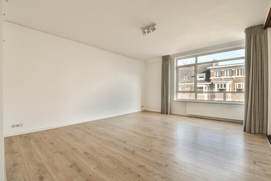 Empty living room with large window and white walls