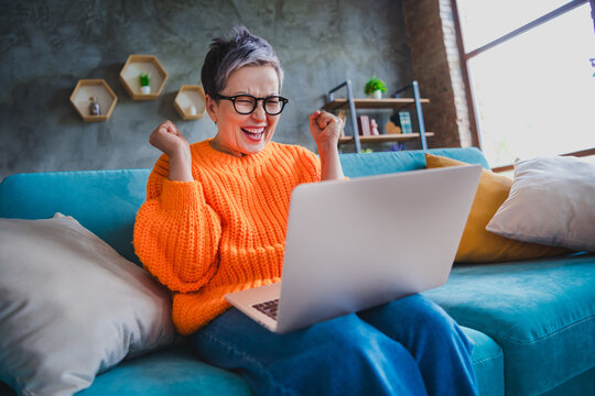 Photo of smiling excited elderly lady wear orange pullover online shopping modern device indoors apartment room