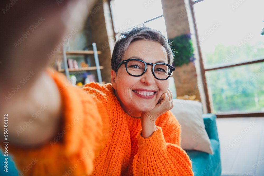 Sticker photo of dreamy pretty elderly lady wear orange pullover spectacles arm hand cheek recording video i