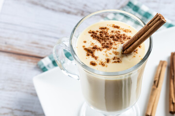 Homemade eggnog with cinnamon on wooden table. Typical Christmas dessert. Close up.