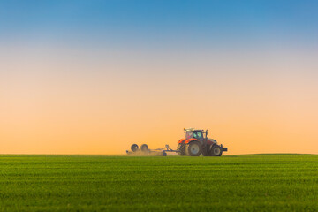 Tractor with a roller tillage on spring field. Soil rolling supports germination and is the basis for good harvesting, organic farming and agronomy - 658194924