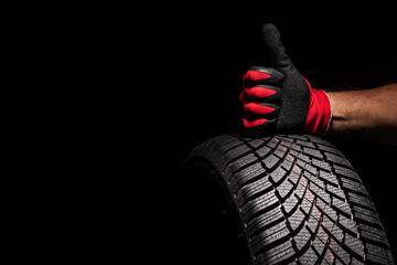 Car tire service and hands of mechanic holding new tyre on black background with copy space for text - 658196161