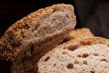 Cut loaf of bread and pieces of bread on a wooden background. Ciabatta bread.