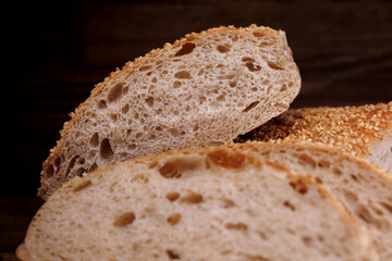 Cut loaf of bread and pieces of bread on a wooden background. Ciabatta bread.