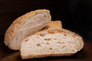 Cut loaf of bread and pieces of bread on a wooden background. Ciabatta bread.