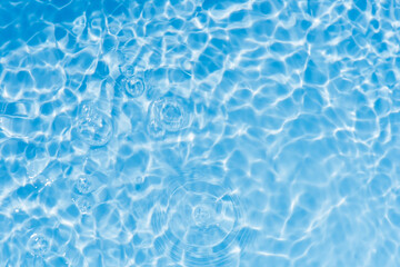 Defocus blurred transparent blue colored clear calm water surface texture with splashes reflection. Trendy abstract nature background. Water waves in sunlight with copy space. Blue watercolor shine.