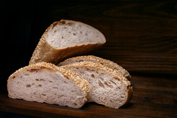 Cut loaf of bread and pieces of bread on a wooden background. Ciabatta bread.