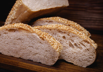 Cut loaf of bread and pieces of bread on a wooden background. Ciabatta bread.