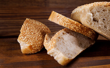 Cut loaf of bread and pieces of bread on a wooden background. Ciabatta bread.