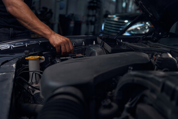 Obraz na płótnie Canvas Close-up hand of male auto-mechanic checking battery terminals