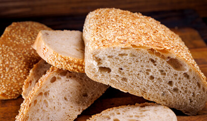 Cut loaf of bread and pieces of bread on a wooden background. Ciabatta bread.