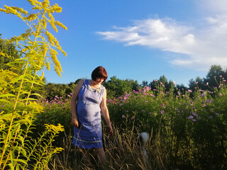 A woman takes a walk in a field. woman takes a walk in a field. She admires the field plants. 