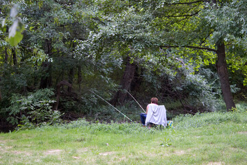 A person sitting in a chair with fishing poles in the woods